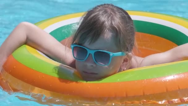 Retrato da menina feliz da criança que relaxa no círculo inflável na piscina no dia ensolarado do verão durante férias tropicais. Conceito de atividades de verão — Vídeo de Stock