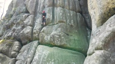 Genç adam dik kayalık dağ duvarına tırmanıyor. Erkek tırmanışçı zorlu rotayı aşar. Ekstrem spor konseptine dalmak