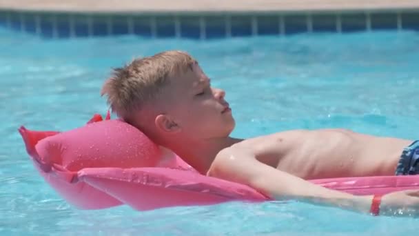 Niño feliz que se relaja en el colchón inflable del aire en la piscina en día soleado del verano durante vacaciones tropicales. Concepto de actividades de verano — Vídeo de stock