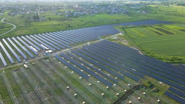 Luchtfoto van een grote elektrische centrale in aanbouw met vele rijen zonnepanelen op metalen frame voor de productie van schone elektrische energie. Ontwikkeling van hernieuwbare energiebronnen — Stockvideo
