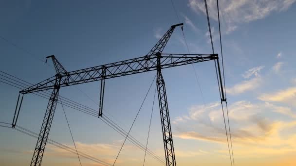 Donker silhouet van hoogspanningstoren met elektrische leidingen bij zonsopgang. Transmissie van het concept elektrische energie — Stockvideo