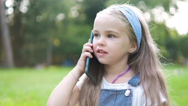 여름 공원에서 핸드폰으로 대화하는 예쁜 여자 애야. 여름 공원에서 휴대 전화로 대화를 나누는 어린 소녀 — 비디오