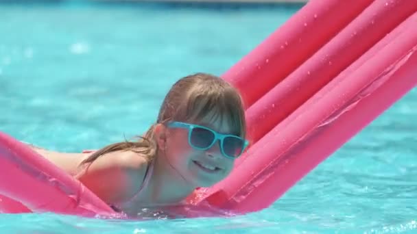 Young child girl falling in water from inflatable air mattress in swimming pool while swinnimg during tropical vacations. Safety of aquatic activities concept — Stock Video