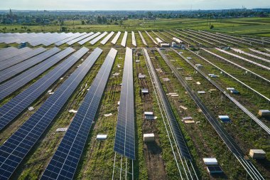 Metal çerçevede temiz elektrik enerjisi üreten birçok sıra güneş paneli bulunan büyük elektrik santralinin havadan görüntüsü. Yenilenebilir elektrik kaynaklarının geliştirilmesi