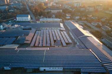 Sanayi binasının çatısına yeşil ekolojik elektrik üretmek için monte edilmiş mavi fotovoltaik panelli güneş enerjisi santralinin hava görüntüsü. Sürdürülebilir enerji konsepti üretimi