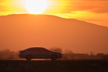 Gün batımında şehir içi yolda hızlı giden bir araba. Akşamları otoyol trafiği