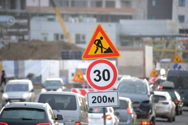 Yol çalışmaları trafik işaretlerini uyardı. Şehir caddesinde inşaat çalışması ve yavaş hareket eden arabalar.