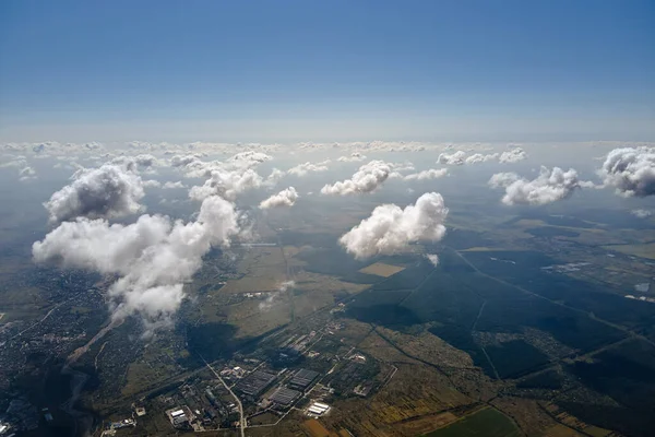 Letecký pohled z okna letadla ve vysoké nadmořské výšce země pokrytý bílými nadýchanými kumulativními mraky — Stock fotografie