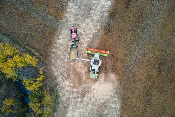 Vue aérienne de la moissonneuse-batteuse déchargeuse de grain dans une remorque de chargement travaillant pendant la saison de récolte sur un grand champ de blé mûr. Agriculture et transport des produits agricoles bruts concept — Photo