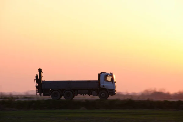 Vrachtwagen dumpen rijden op de snelweg vervoeren goederen in de avond. Levering transport en logistiek concept — Stockfoto