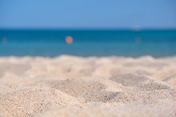 Zbliżenie czystej żółtej powierzchni piasku pokrywającej nadmorską plażę błękitną wodą morską na tle. Koncepcja podróży i wakacji — Zdjęcie stockowe