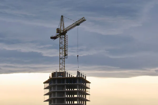 Gün batımında yüksek apartmanlı inşaat alanındaki vinçlerin koyu renkli silueti. Gayrimenkul geliştirme — Stok fotoğraf