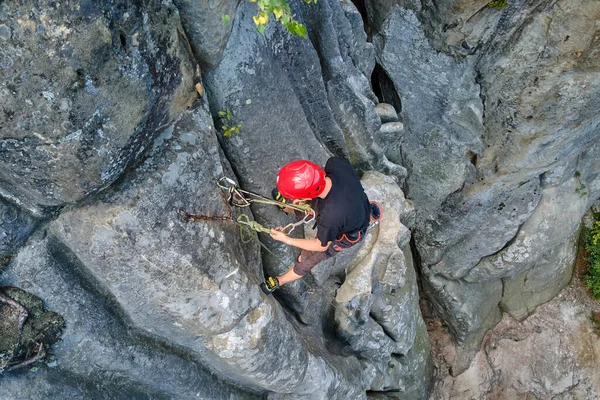 Vastberaden klimmer klautert omhoog steile muur van rotsachtige berg. Sportman overwint moeilijke route. Betrokken bij extreme sporten en rotsklimmen hobby concept — Stockfoto