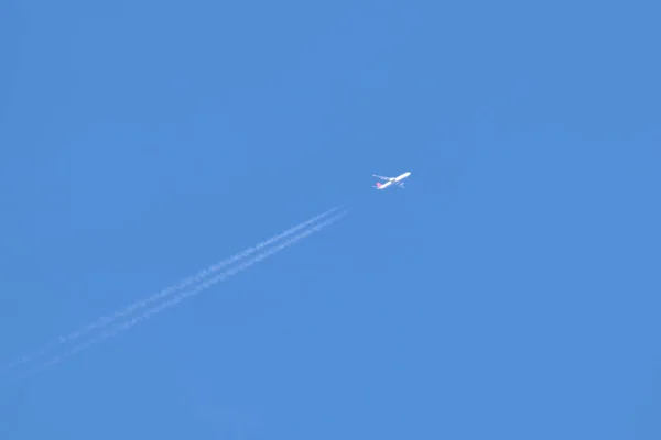 Aereo a reazione passeggeri distanti che volano in alta quota su cielo blu chiaro lasciando tracce di fumo bianco di contrail dietro. Concetto trasporto aereo — Foto Stock