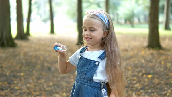 Joyeux petit enfant fille soufflant des bulles de savon à l'extérieur dans un parc vert. Activités d'été en plein air pour enfants concept — Photo