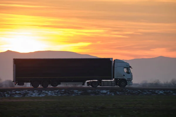 Semi-vrachtwagen met lading aanhangwagen rijden op de snelweg vervoeren goederen in de avond. Levering transport en logistiek concept — Stockfoto