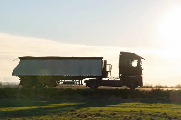 Semi-caminhão com reboque de carga derrubada transportando areia de pedreira dirigindo em mercadorias de transporte rodoviário à noite. Conceito de transporte e logística de entrega — Fotografia de Stock