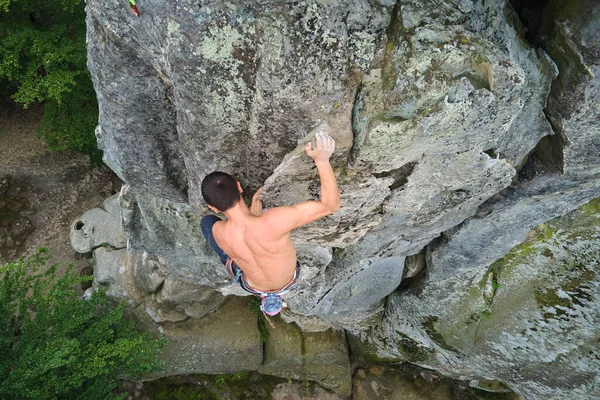 Jeune homme escaladant un mur escarpé de montagne rocheuse. Homme grimpeur surmonte itinéraire difficile. S'engager dans un concept de sport extrême — Photo