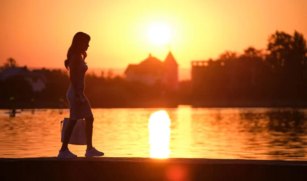 평상복 차림의 젊은 여자가 따뜻 한 저녁에 호수 옆을 걷고 있다. 여름 방학 과 여행의 개념 — 스톡 사진