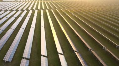 Akşamları temiz elektrik enerjisi üretmek için sıra sıra güneş fotovoltaik panelleri olan sürdürülebilir büyük elektrik santralinin havadan görünüşü. Sıfır emisyonlu yenilenebilir elektrik kavramı