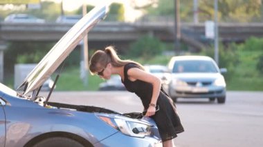 Kaputu açık halde arabasının yanında duran çaresiz bir kadın cep telefonundan yardım için yol servisini arıyor. Genç bayan sürücünün aracıyla ilgili sorunları var