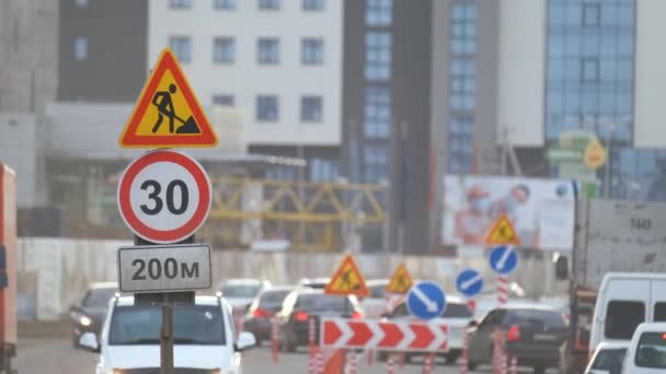 Vägarbeten varnar trafikskyltar för byggnadsarbeten på stadsgatan och långsamgående bilar — Stockvideo