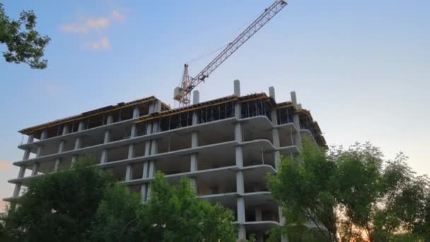 Gru a torre e condominio residenziale alto con struttura monolitica in costruzione al tramonto. Sviluppo immobiliare — Video Stock