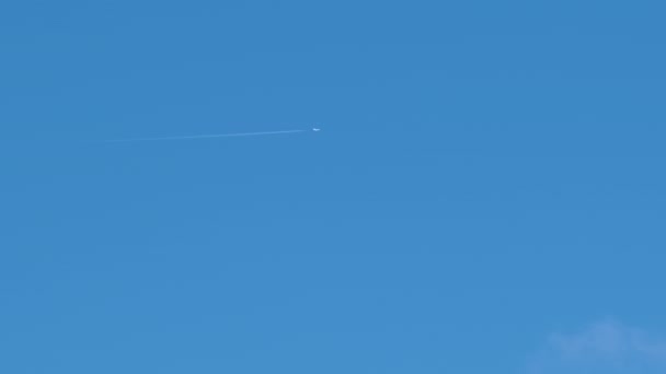 Entfernte Passagierflugzeuge fliegen in großer Höhe bei klarem blauen Himmel und hinterlassen weiße Rauchspuren von Kondensstreifen. Lufttransportkonzept — Stockvideo