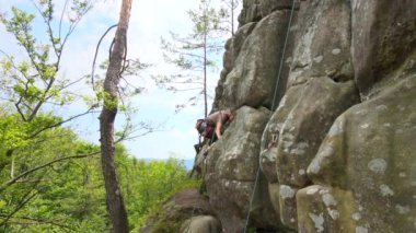Genç adam dik kayalık dağ duvarına tırmanıyor. Erkek tırmanışçı zorlu rotayı aşar. Ekstrem spor konseptine dalmak