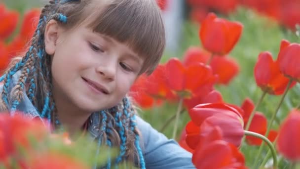 Gelukkig kind meisje spelen in de zomer tuin genieten zoete geur van rode tulp bloemen op zonnige dag — Stockvideo