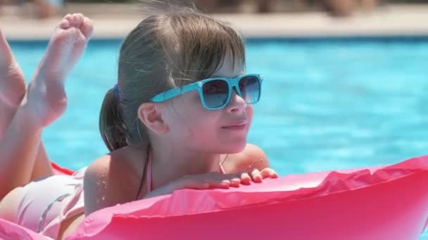 Menina feliz que relaxa no colchão inflável do ar na piscina no dia ensolarado do verão durante férias tropicais. Conceito de atividades de verão — Vídeo de Stock