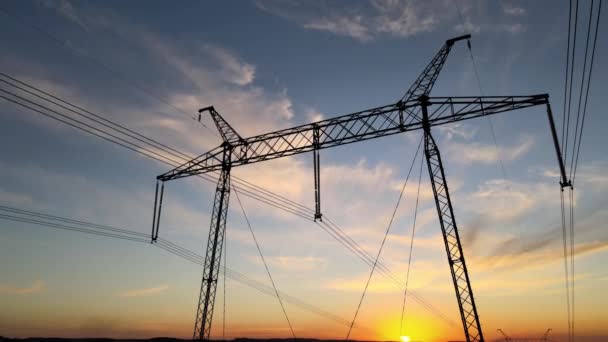 日の出時に電力線と高電圧タワーの暗いシルエット。電気エネルギーの概念の伝達 — ストック動画