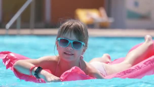 熱帯の休暇に暖かい夏の日に青い水でスイミングプールでインフレータブル空気マットレスで楽しい水泳をしている若い楽しい子供の女の子。夏のアクティビティコンセプト — ストック動画