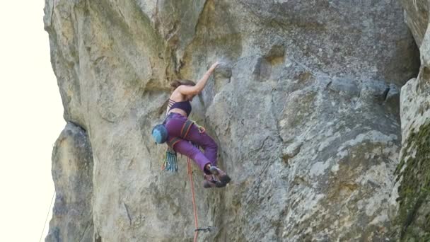 Odhodlaná horolezkyně šplhá po příkré stěně skalnaté hory. Sportovkyně překonává obtížnou cestu. Zapojení do extrémních sportů a horolezectví hobby koncept — Stock video
