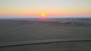 Gün batımında hızlı giden arabalarla şehirlerarası yol manzarası. Akşamları otoban trafiğinin insansız hava aracı görüntüsü