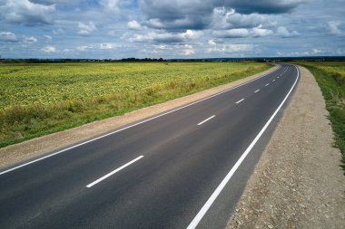 Yeşil tarım alanları arasındaki boş şehirlerarası yolun havadan görünüşü. Karayolu insansız hava aracının üst görüntüsü