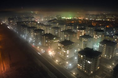 Yüksek katlı apartman binalarının ve şehrin yerleşim alanındaki aydınlık sokakların havadan görüntüsü. Karanlık şehir manzarası