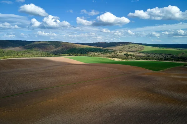 Vista aérea de campos agrícolas arados con suelo fértil cultivado preparado para la siembra de cultivos entre bosques verdes en primavera —  Fotos de Stock