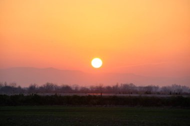Güzel bir akşam panoramik manzarası. Gün batımında güneş batarken uzak dağ tepeleri ve asfalt yolda batıyor.
