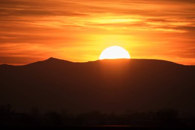 Güzel bir akşam panoramik manzarası. Gün batımında uzak dağ tepeleri üzerinde parlak batan güneş.