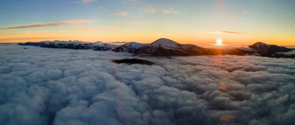 Vista aérea del vibrante amanecer sobre la densa niebla blanca con lejanas montañas oscuras de los Cárpatos en el horizonte —  Fotos de Stock