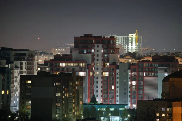 Architektoniczne detale nowoczesnych wysokich budynków mieszkalnych z wieloma oświetlonymi oknami i balkonami w nocy — Zdjęcie stockowe