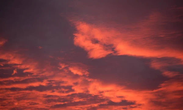 Яскраве барвисте небо заходу сонця з яскравими гладкими хмарами, освітленими встановленням сонячного світла, що поширюється на горизонт — стокове фото
