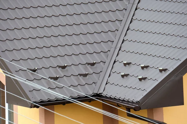 Protector de nieve para la seguridad en invierno en la azotea de la casa cubierta con tejas de acero. Revestimiento de azulejos del edificio — Foto de Stock