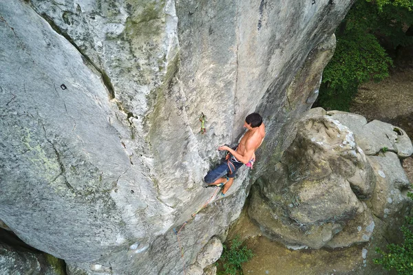 Jeune homme escaladant un mur escarpé de montagne rocheuse. Homme grimpeur surmonte itinéraire difficile. S'engager dans un concept de sport extrême — Photo