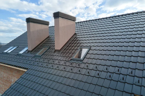 Fechar as janelas do sótão e chaminés de tijolo no telhado da casa coberto com telhas de cerâmica. Cobertura de edifício empilhada — Fotografia de Stock