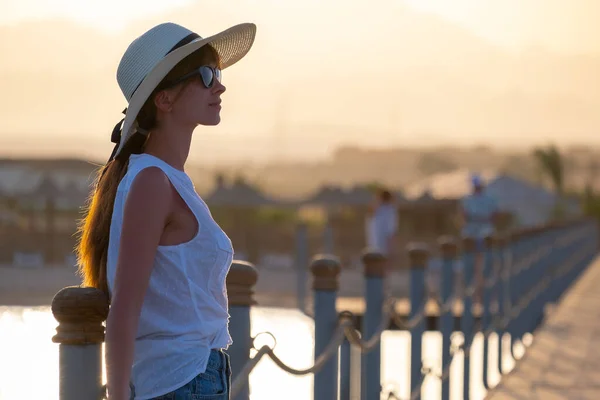 Donna felice rilassarsi all'aperto sul ponte dell'hotel sulla riva del mare godendo di calda serata tropicale. Vacanze estive e concetto di viaggio — Foto Stock