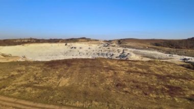 Kazı makineleri ve çöp kamyonlarıyla inşaat endüstrisi için kumtaşı malzemelerinden oluşan açık maden manzarası. Madencilik ve kullanışlı mineral üretiminde ağır ekipman