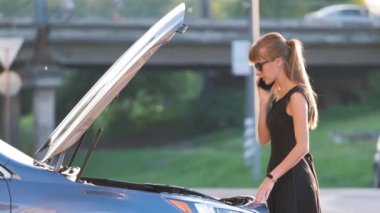 Kaputu açık bir şekilde arabasının yanında duran çaresiz kadın yardım için yol servisini arıyor. Genç bayan sürücünün aracıyla ilgili sorunları var