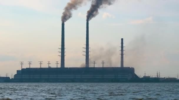 Hoge pijpen van kolencentrales met zwarte rook die naar boven beweegt, vervuilende atmosfeer boven meer water — Stockvideo